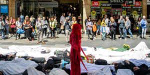 Image of a "die in" in a mall in South Australia, with people in white on the ground and a lone woman in red standing