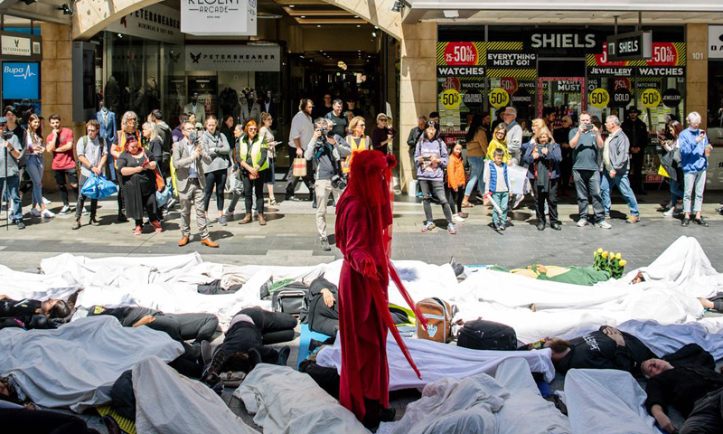 Image of a "die in" in a mall in SA, with people in white on the ground and a lone woman in red standing